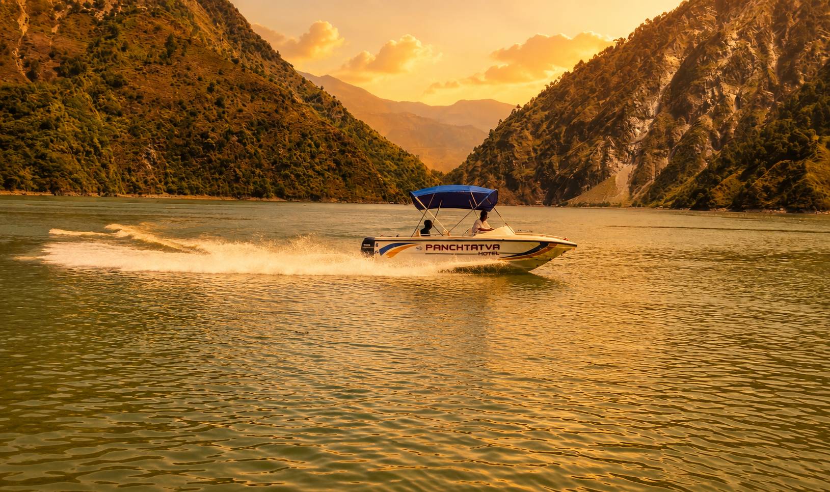 Guests boating on Chamera Lake surrounded by Himalayan mountains and forested hills